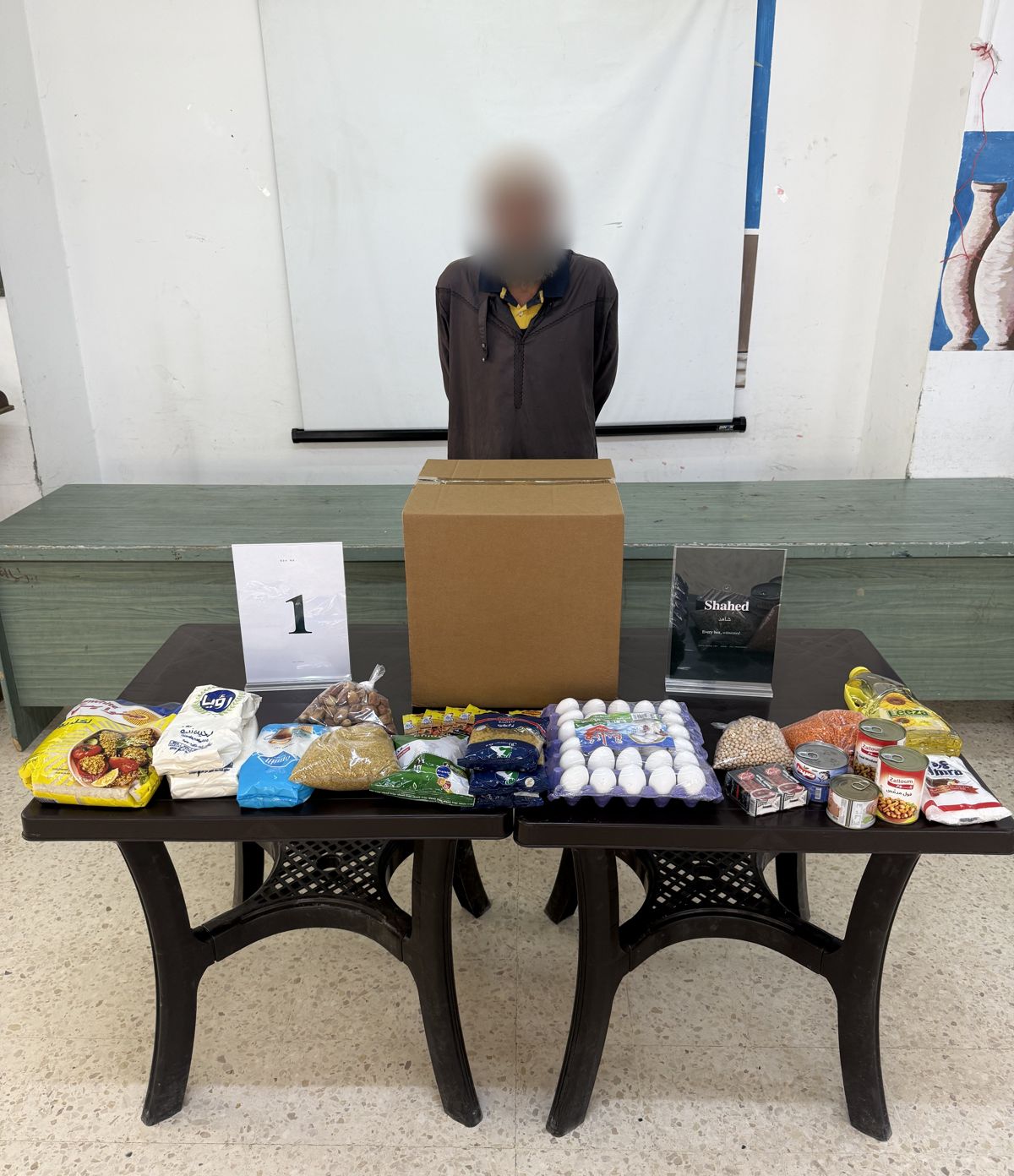 Box №01 handed to a family in Gaza Camp, Jerash. The recipient's face is blurred.